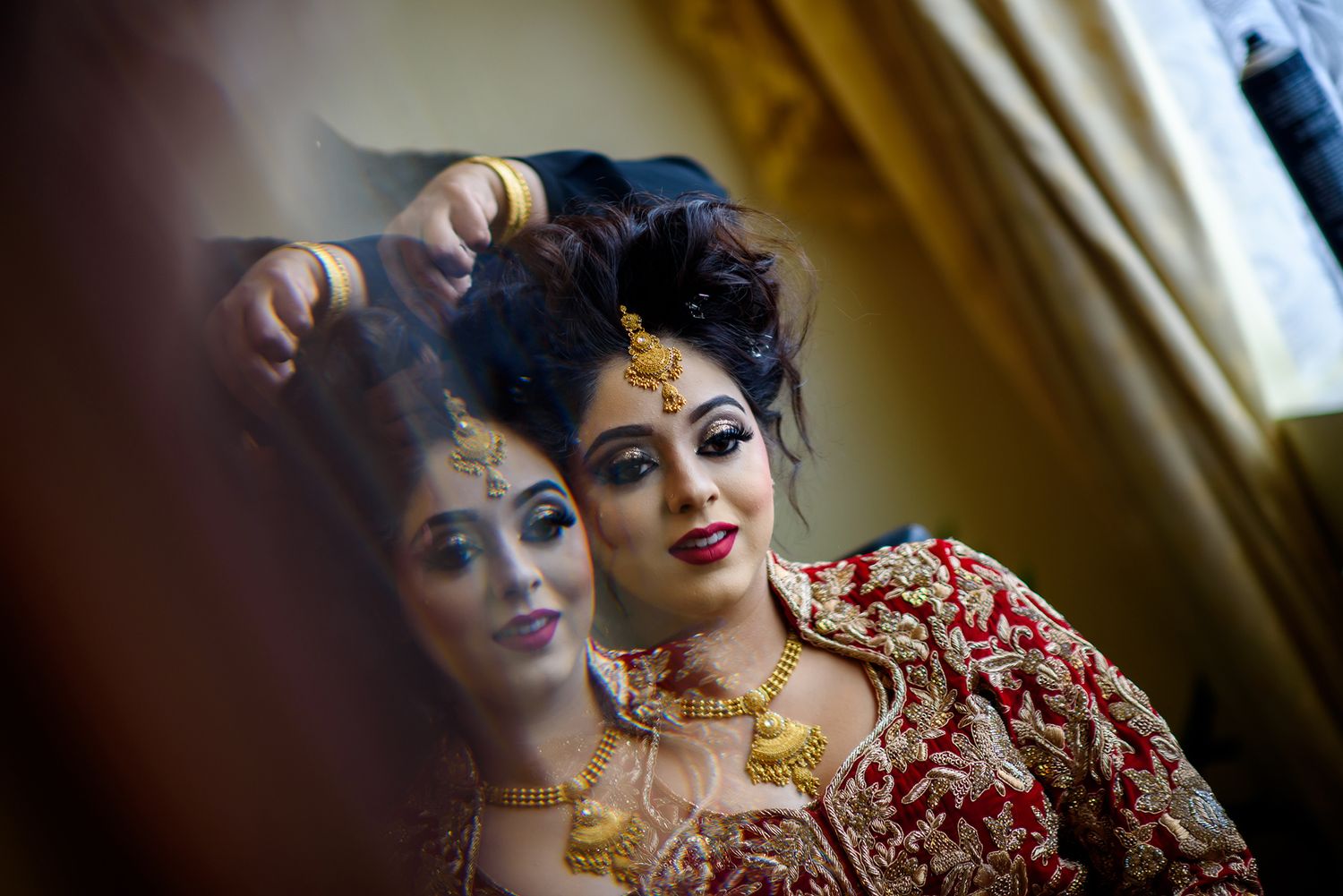 Artistic wedding preparation photo with red and gold traditional attire.