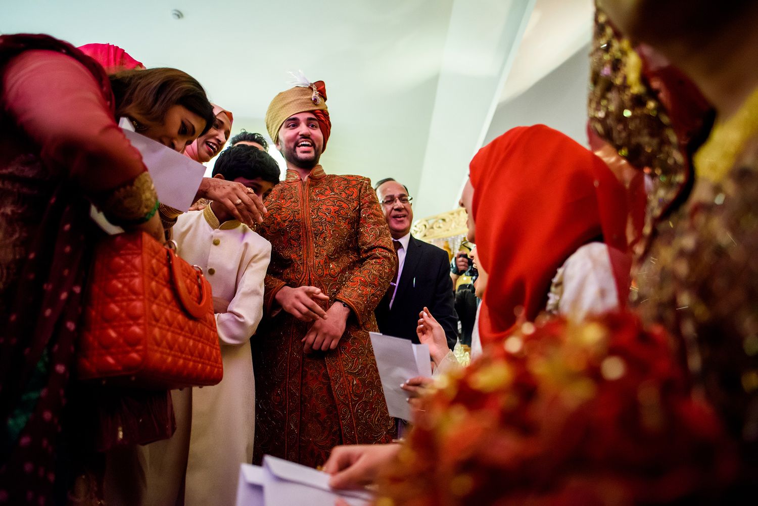Traditional South Asian wedding ceremony with guests in vibrant red and gold attire.