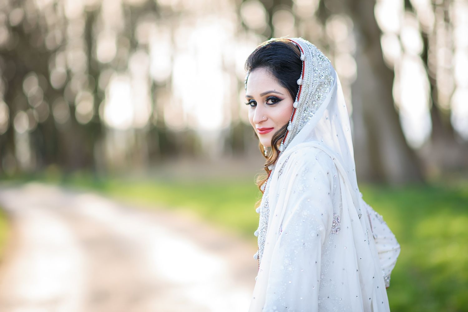 Dreamy outdoor portraits featuring white traditional wedding attire against a natural backdrop.