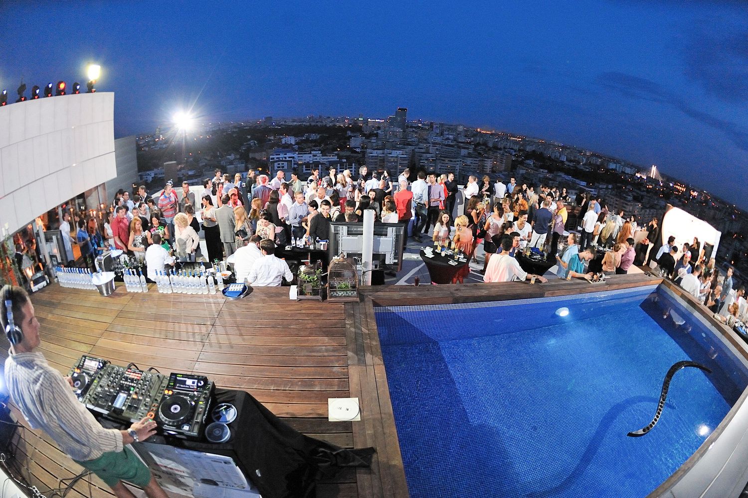 Large crowd gathered at outdoor waterfront venue during blue hour.