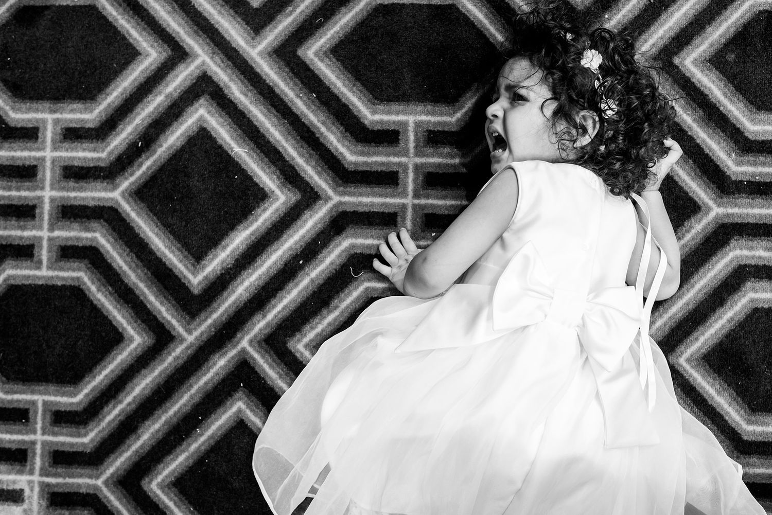 Black and white photo of a reception with an art deco geometric pattern backdrop and dancing guests.