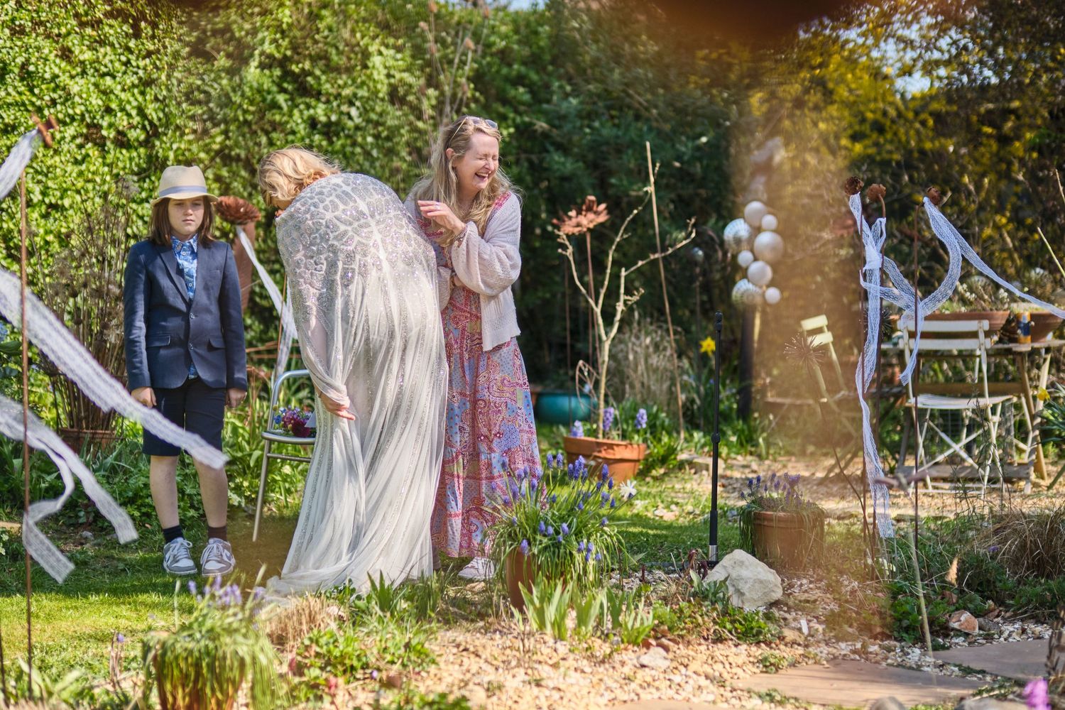 People enjoying a sunny outdoor celebration in a lush garden setting with decorative elements.