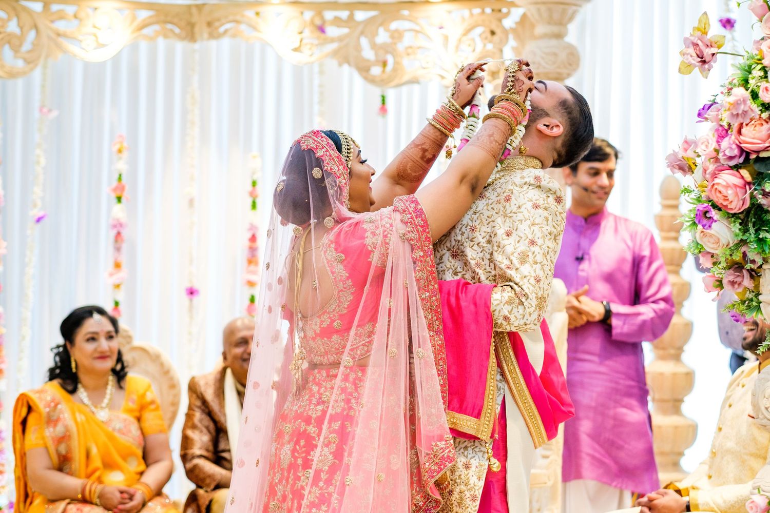 Joyous wedding ceremony moment with traditional rituals and pink floral decorations.