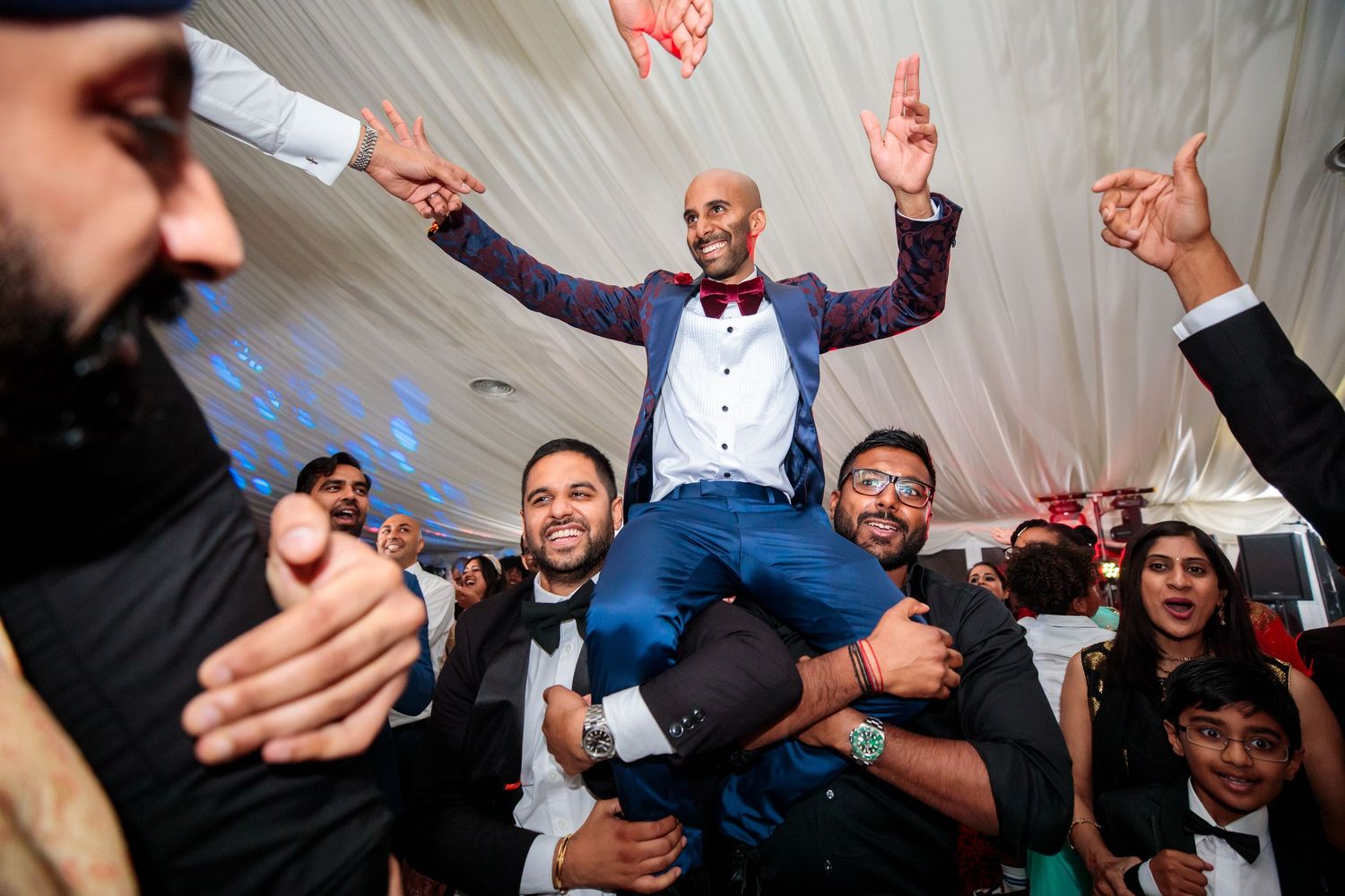 Energetic wedding reception dance floor with guests celebrating and dancing.