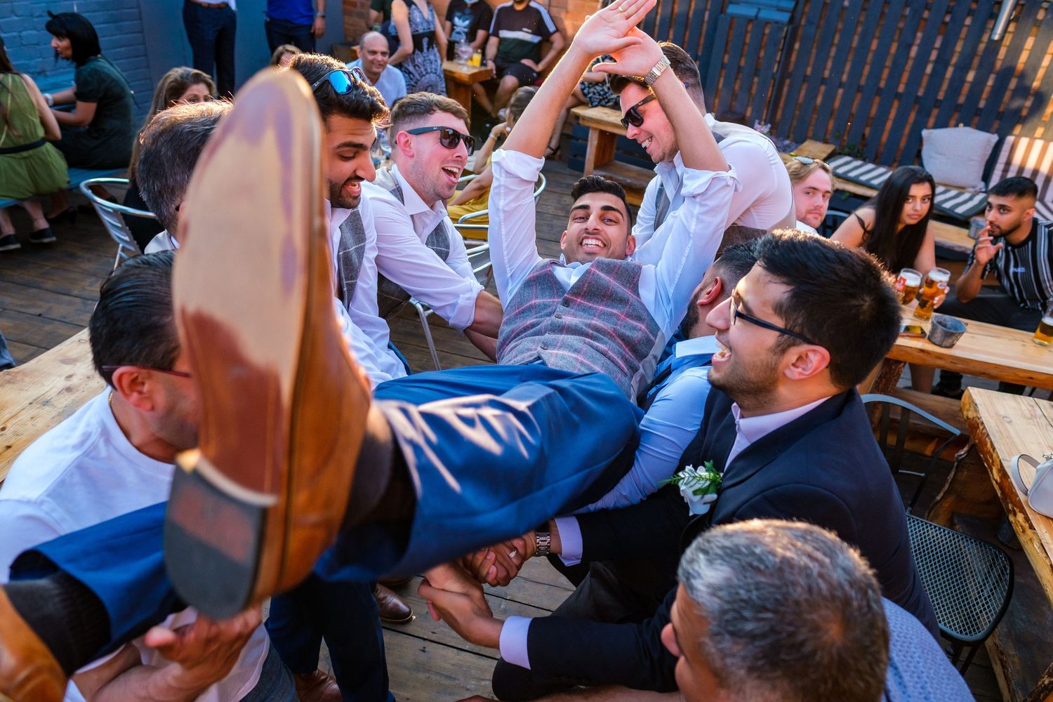 Wedding guests enjoying outdoor reception celebration on patio.
