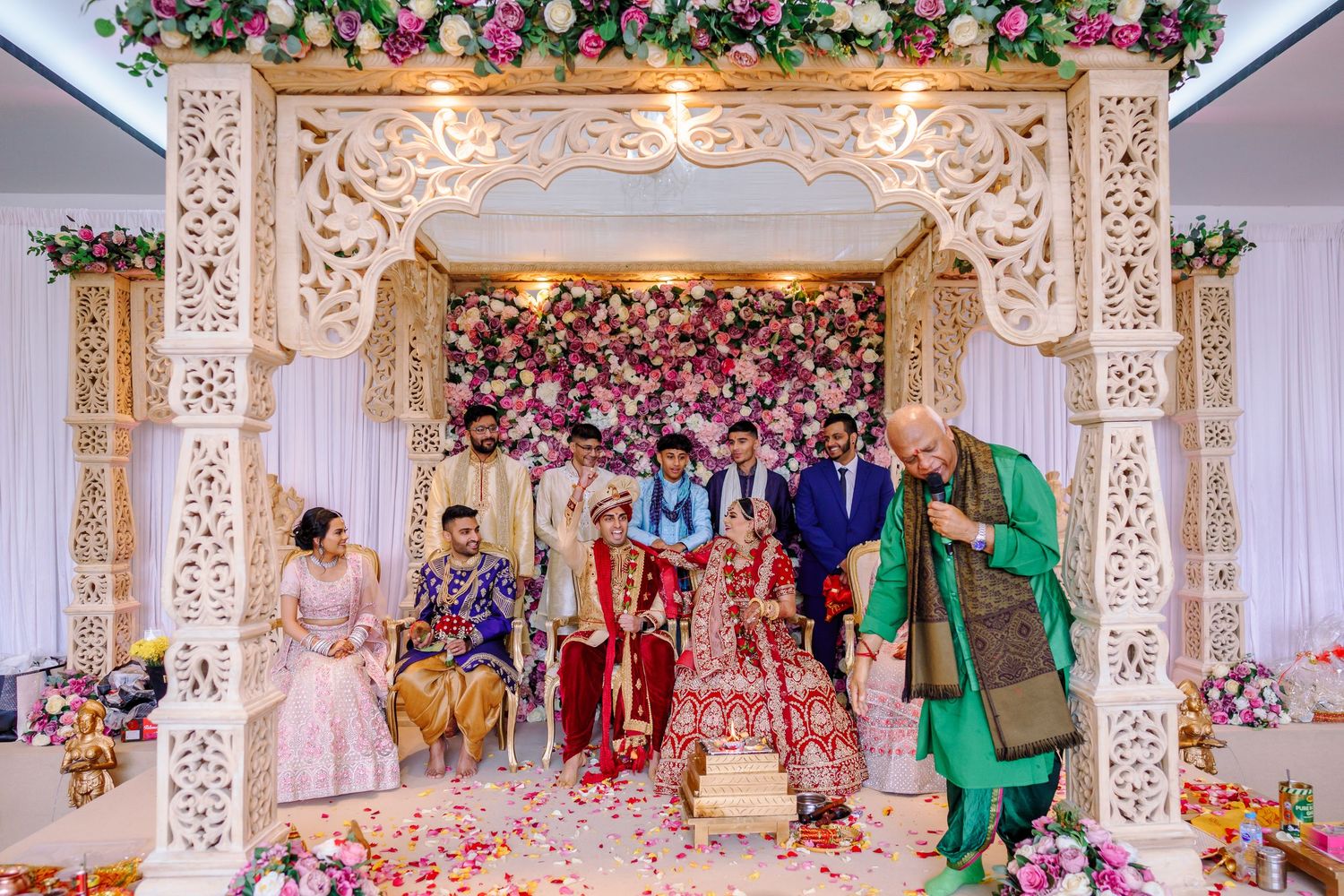 Ornate mandap decorated with pink flowers and intricate carved details during an Indian wedding ceremony.