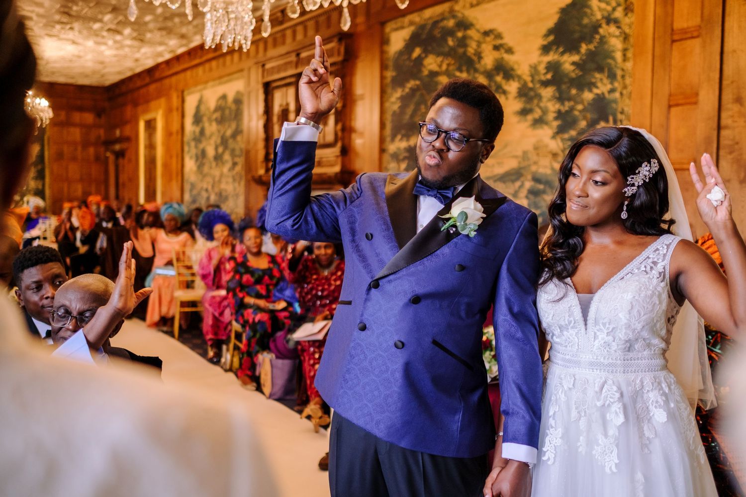 Wedding celebration with guests dancing and enjoying festivities in an ornate indoor reception hall.
