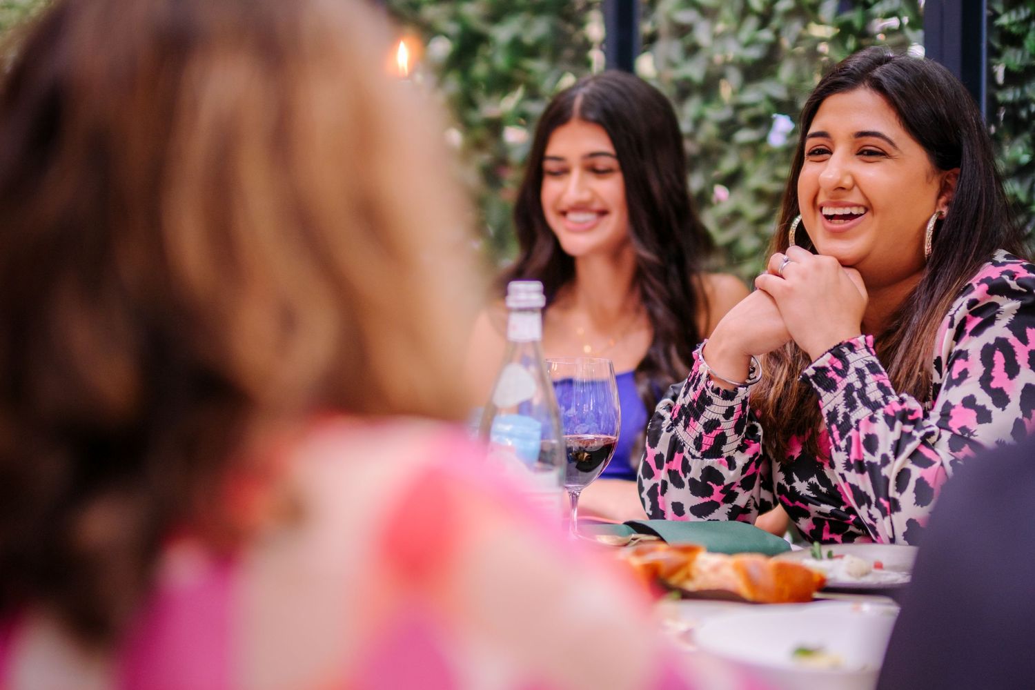 Wedding guests enjoying a meal at an outdoor reception under floral decorations.