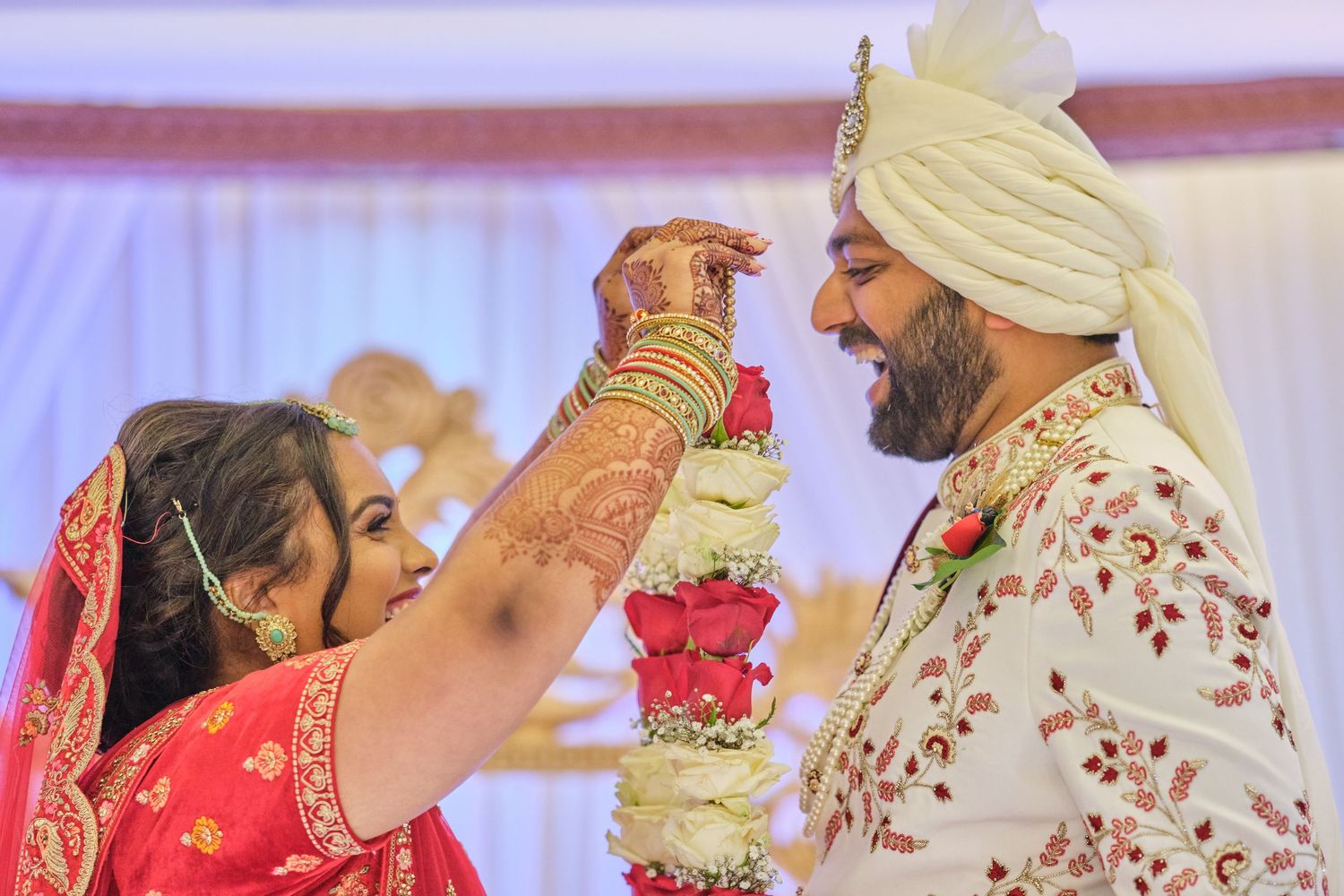 Traditional Indian wedding ceremony with decorative mandap and floral arrangements in red and gold colors.