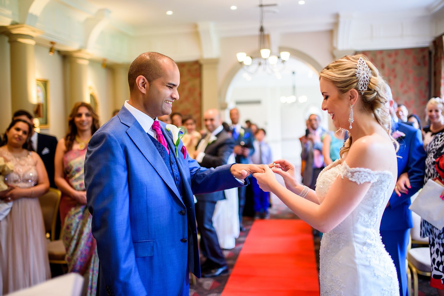 Wedding celebration in an elegant ballroom with columns and decorative lighting.
