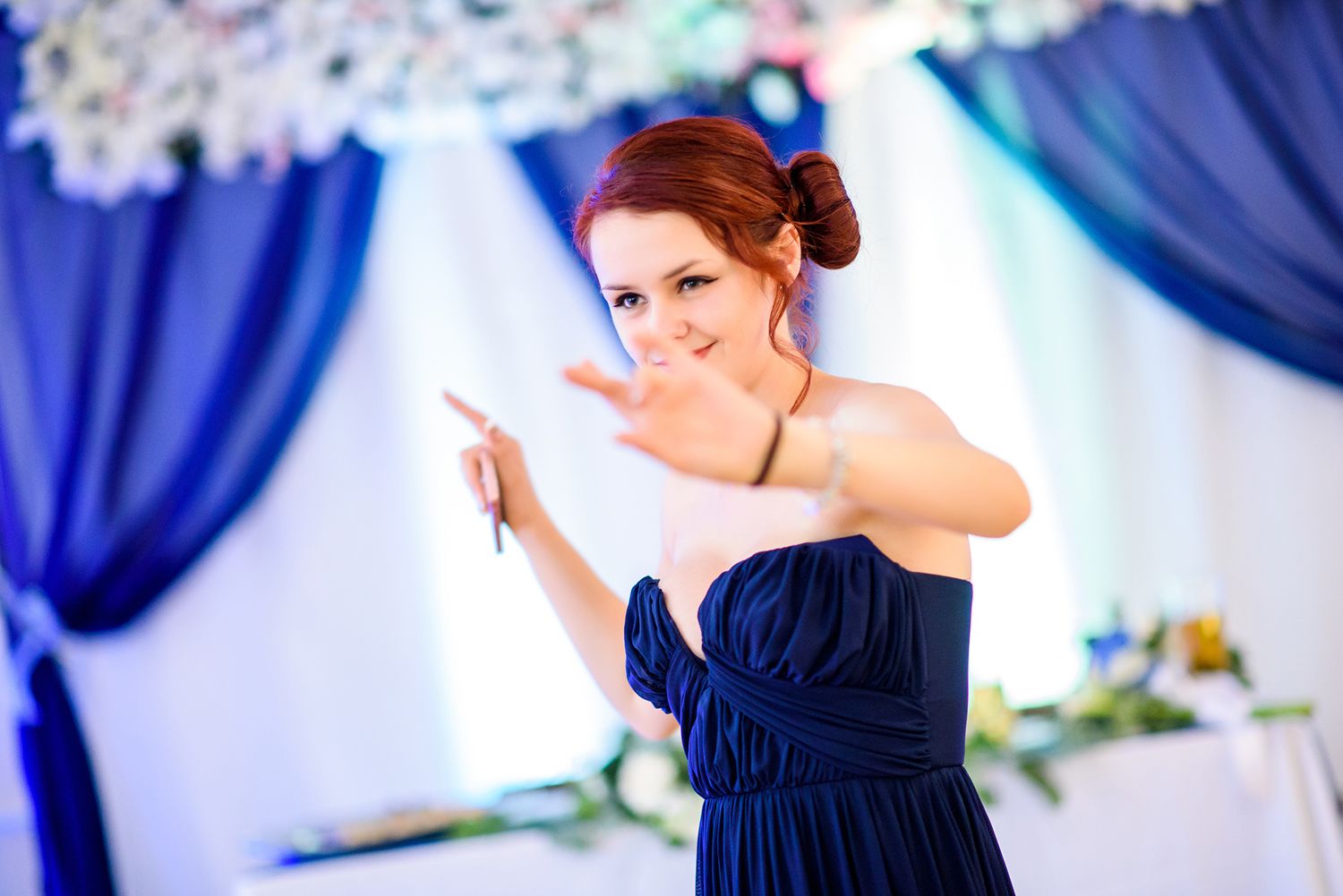 Wedding reception decorated with royal blue drapes and elegant floral arrangements.