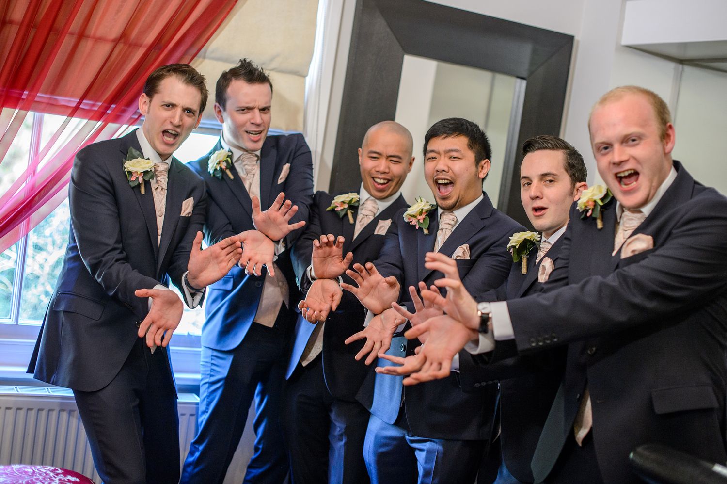 Wedding party members in formal attire cheering and celebrating together.