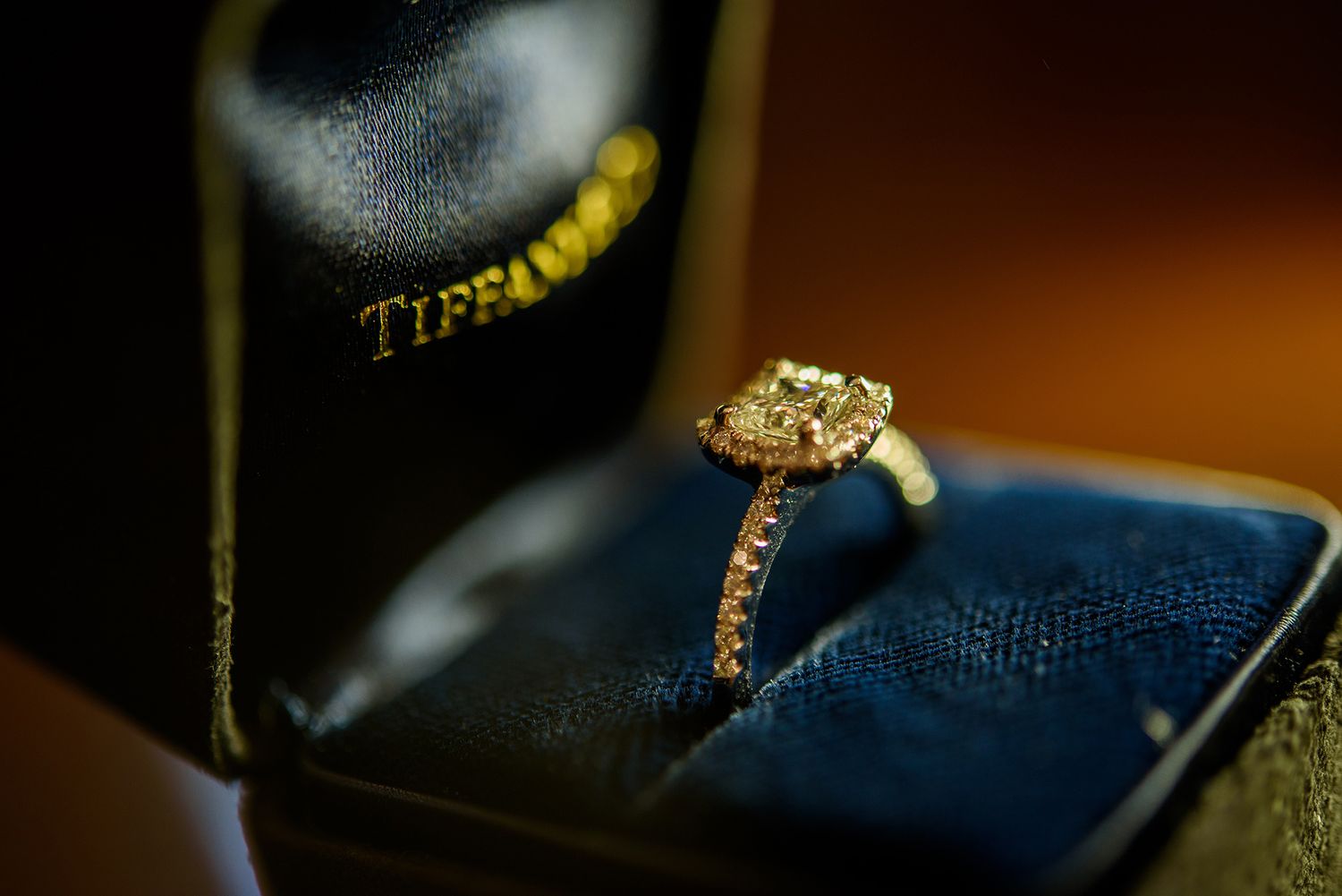 Close-up macro shot of a diamond engagement ring on blue velvet.