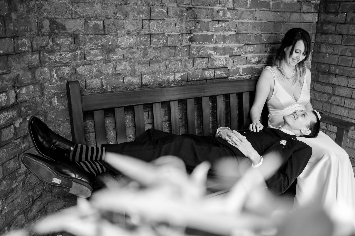 Wedding scene against rustic brick wall with wooden bench details.