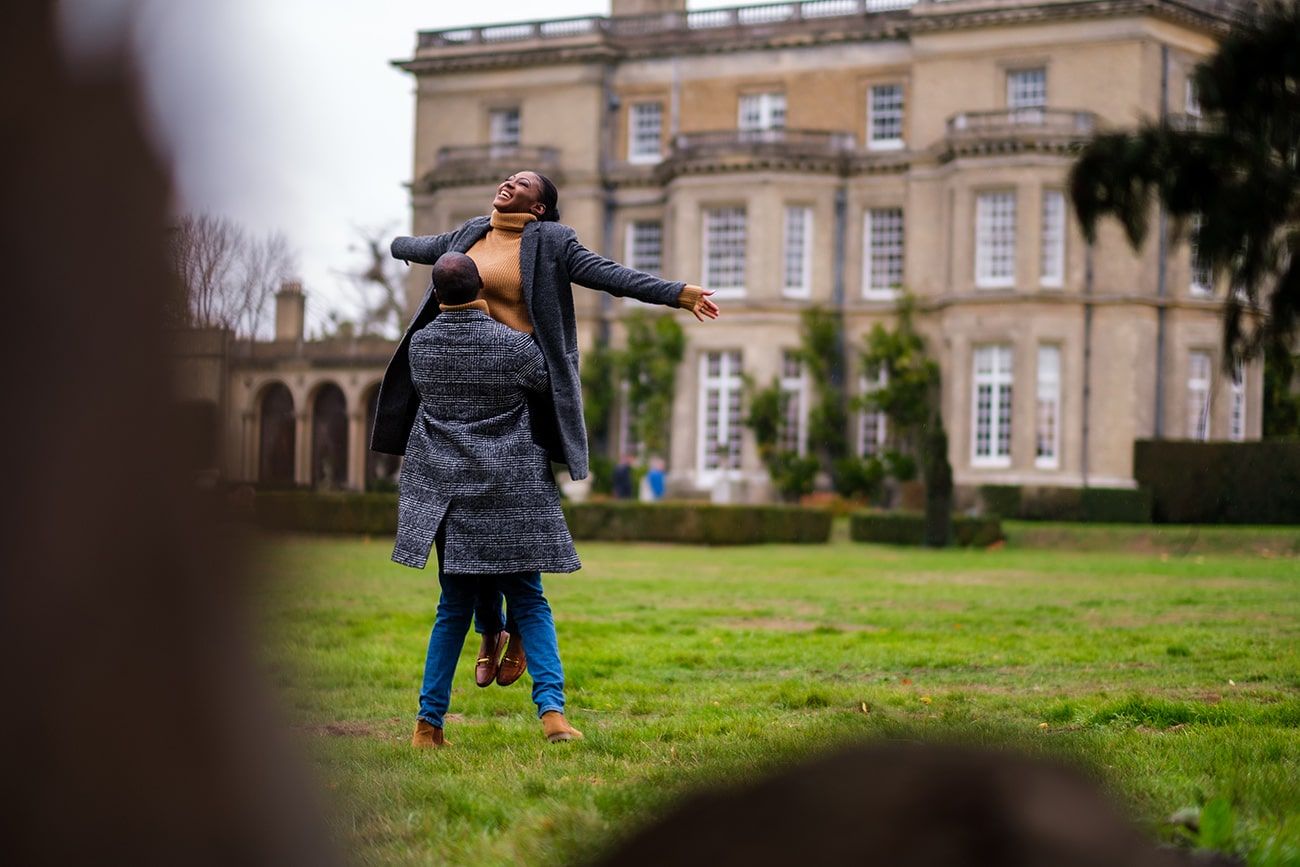 A grand historic mansion with stone facade and manicured grounds on a cloudy day.