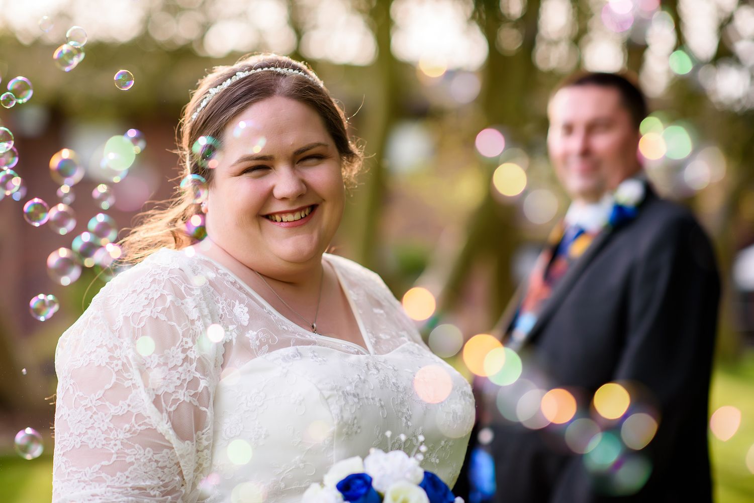 Soap bubbles float through the air at a garden wedding celebration.