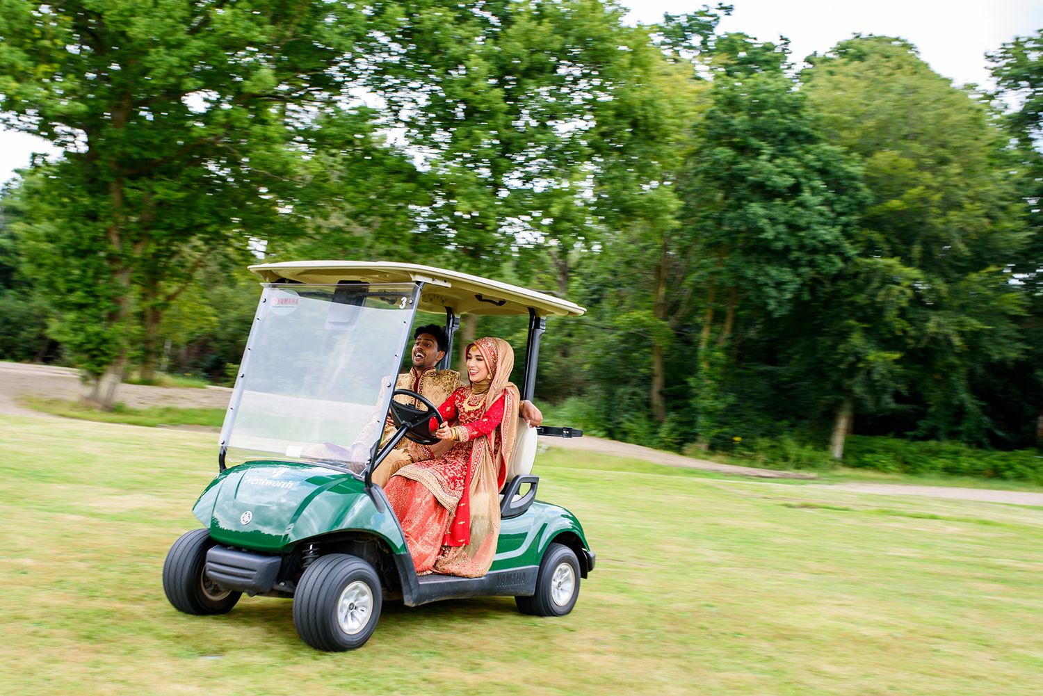 Golf cart procession moves across expansive green lawn during outdoor event.