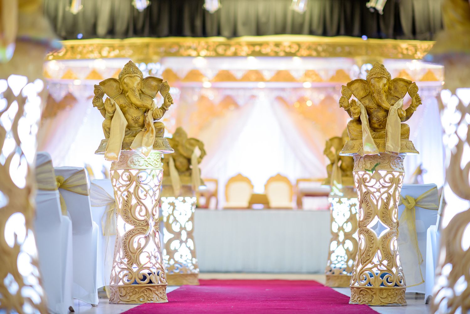 Luxurious Indian wedding venue decorated with ornate gold details and elegant white draping.