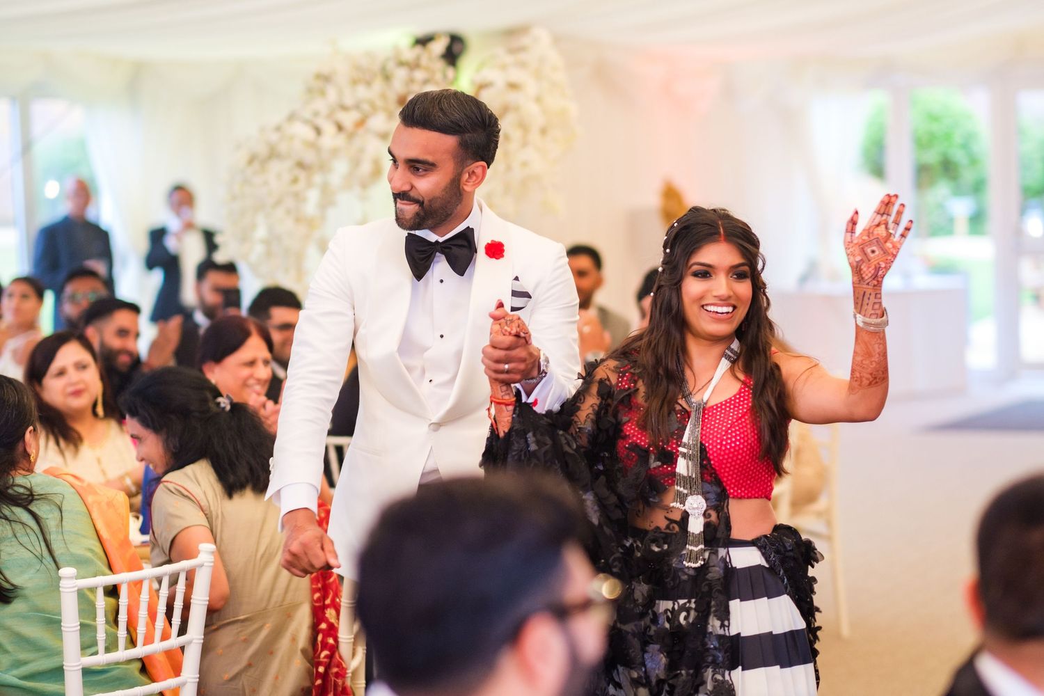 Wedding reception venue decorated with white chairs and elegant lighting for indoor celebration.