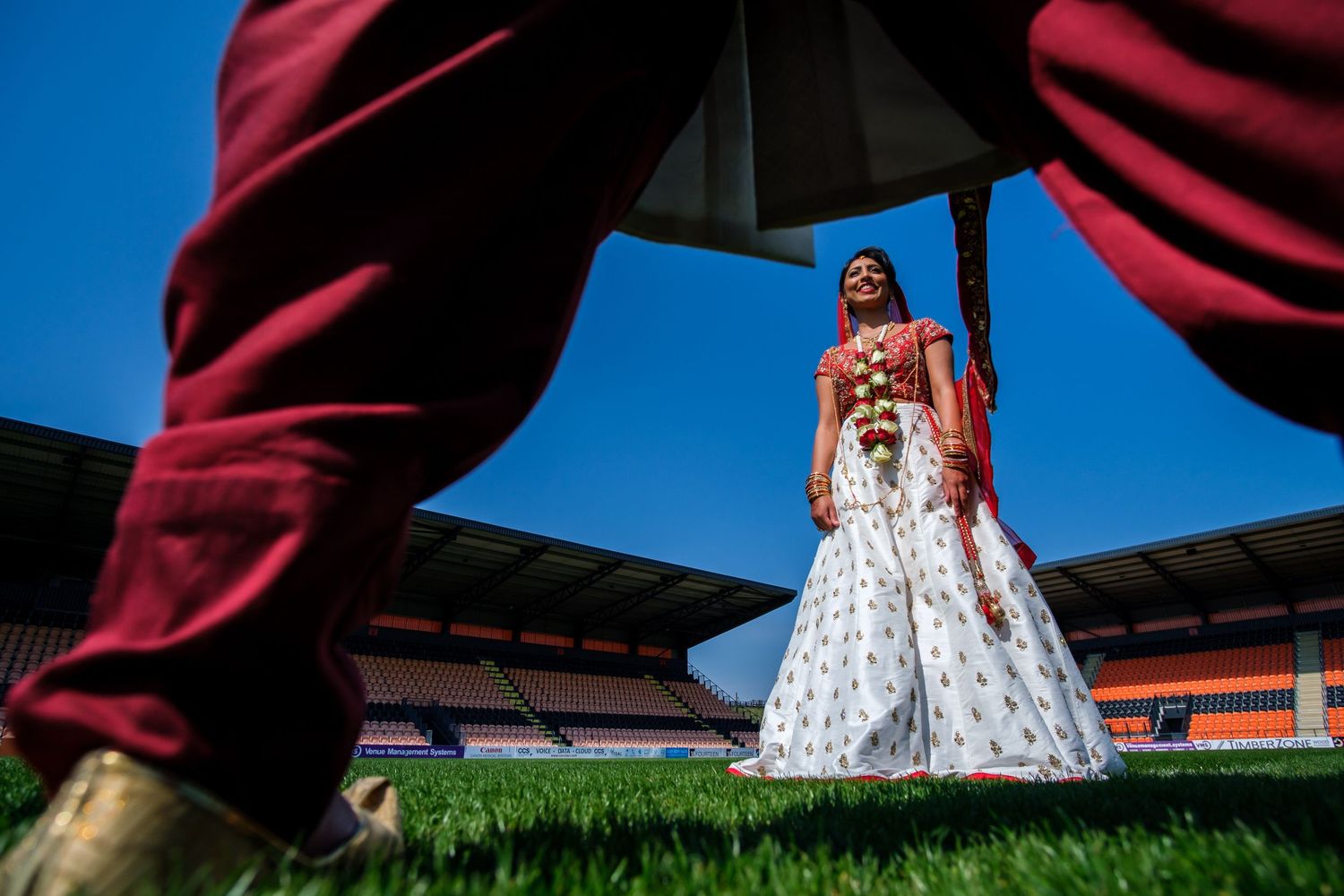 Creative outdoor wedding photography with dramatic angles against blue sky.