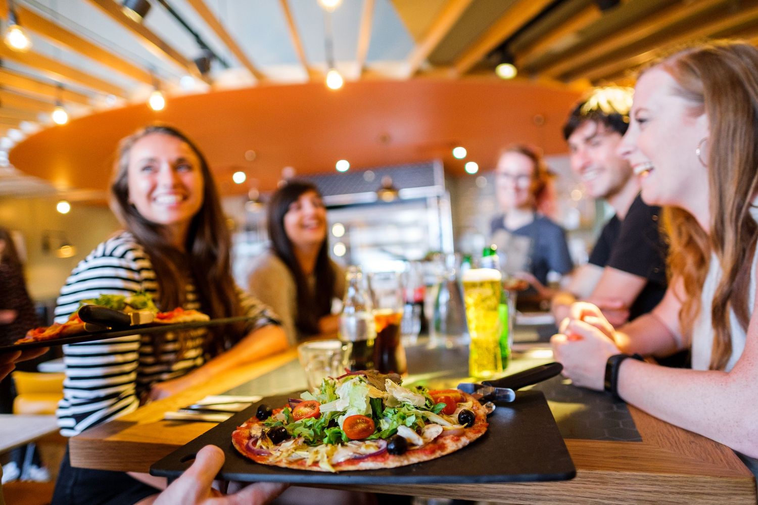 Diners enjoying meals and drinks at a casual restaurant with warm lighting.