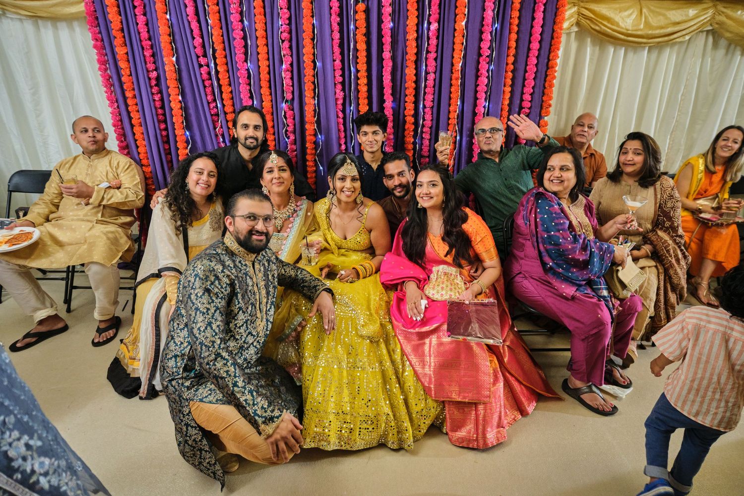 Guests in colorful traditional attire dancing and celebrating at an Indian wedding reception party.