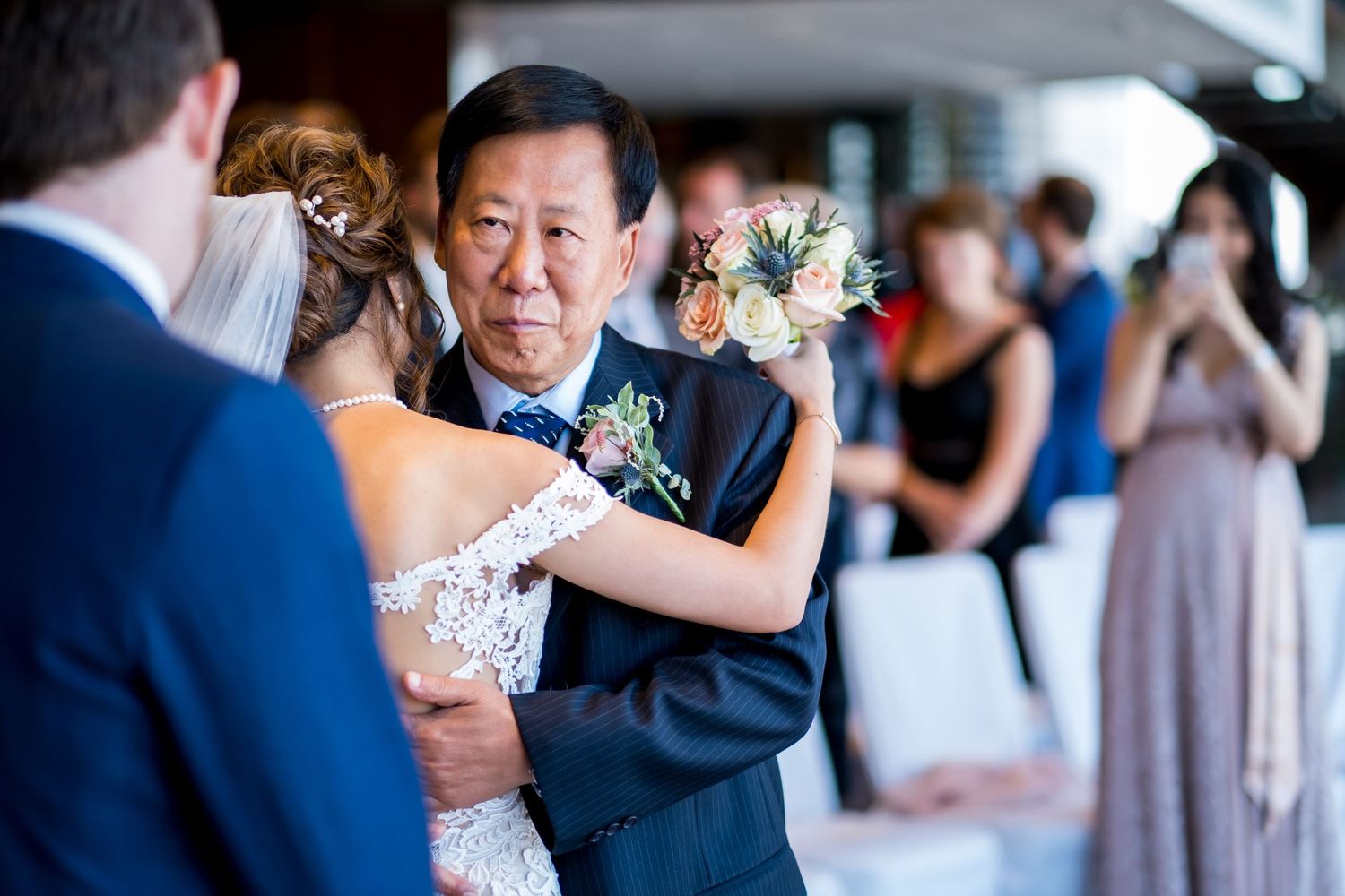 Emotional moment during a wedding ceremony as guests watch a traditional father-daughter dance.