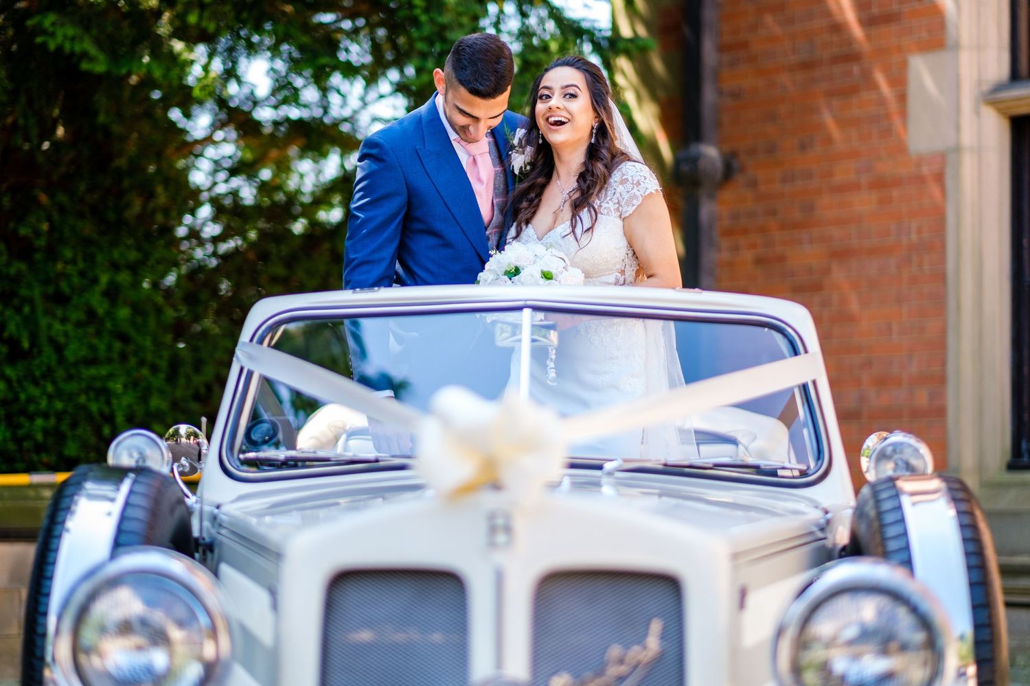 Classic white vintage car decorated with ribbons for a wedding celebration.