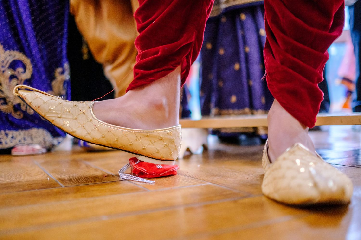 Close-up of traditional Indian wedding footwear with red powder during a cultural ceremony.