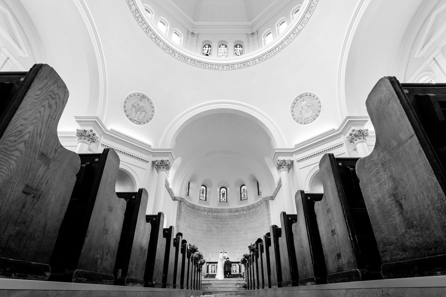 Black and white architectural photo of a church interior with dramatic arches and wooden pews.