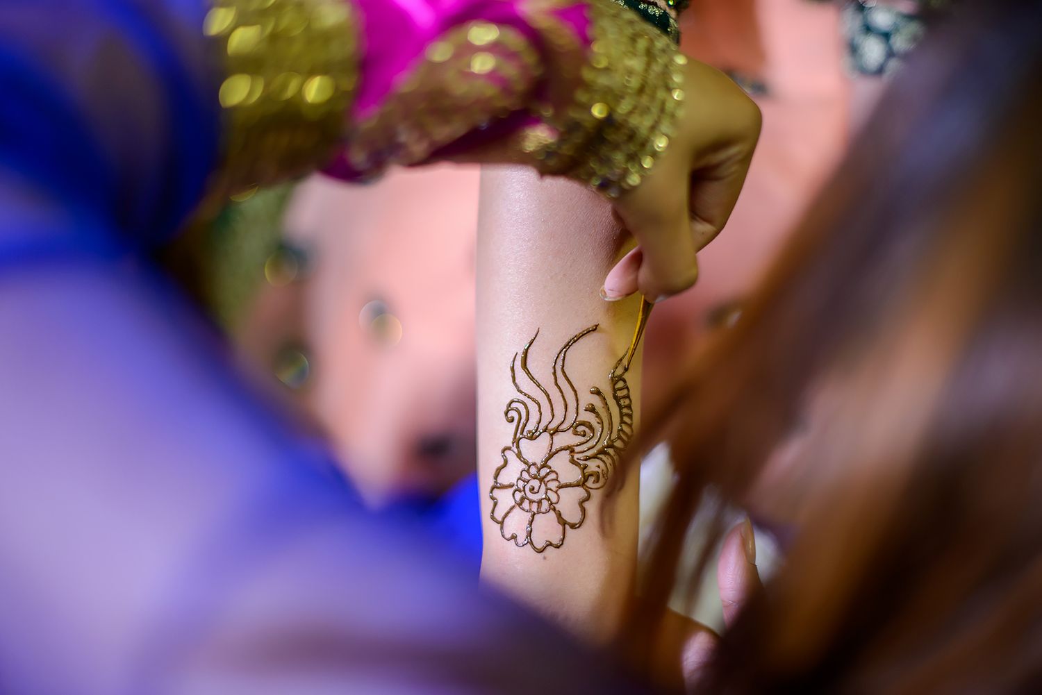 Artistic close-up of traditional mehndi designs with selective focus and purple lighting.