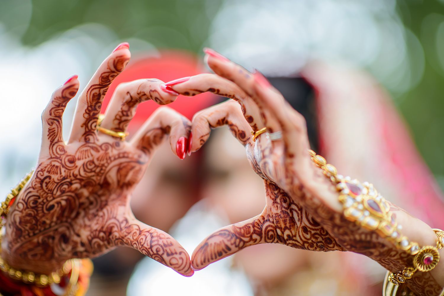 Detailed shots of henna-decorated hands with gold jewelry against a blurred green background.