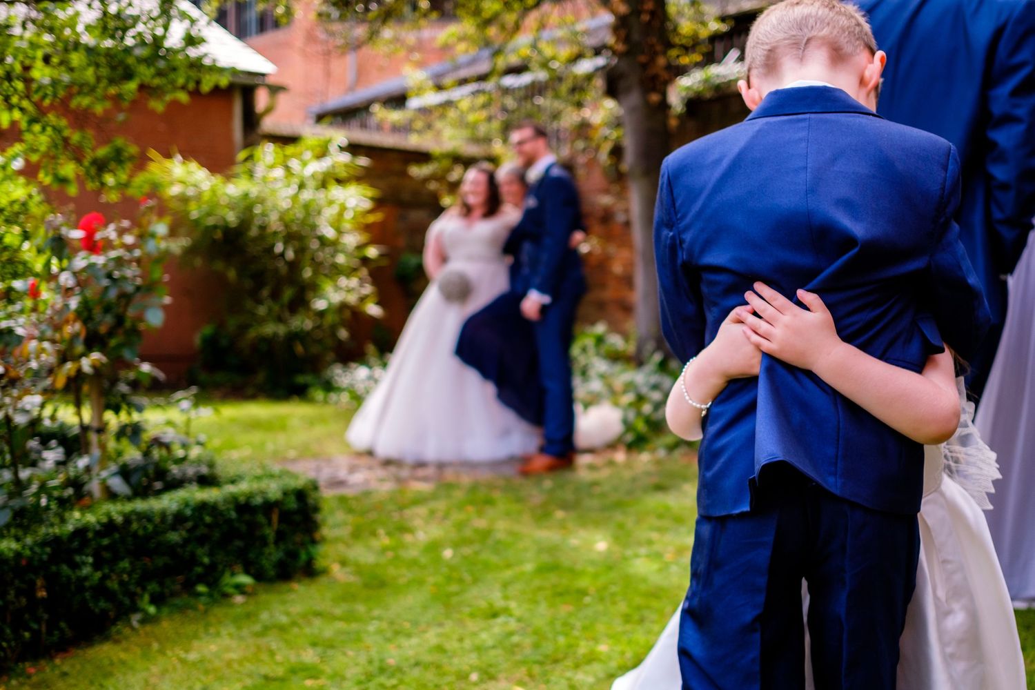 Couple dancing together in a garden setting with trees and flowers in the background.