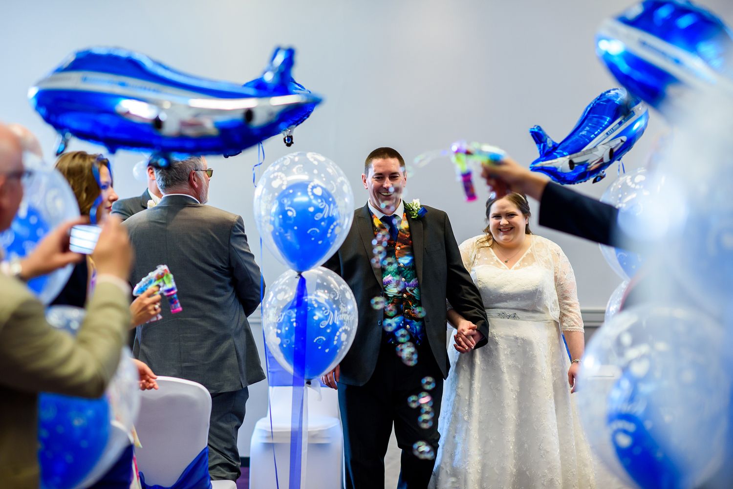Wedding celebration guests playing with blue bubbles during an outdoor reception.