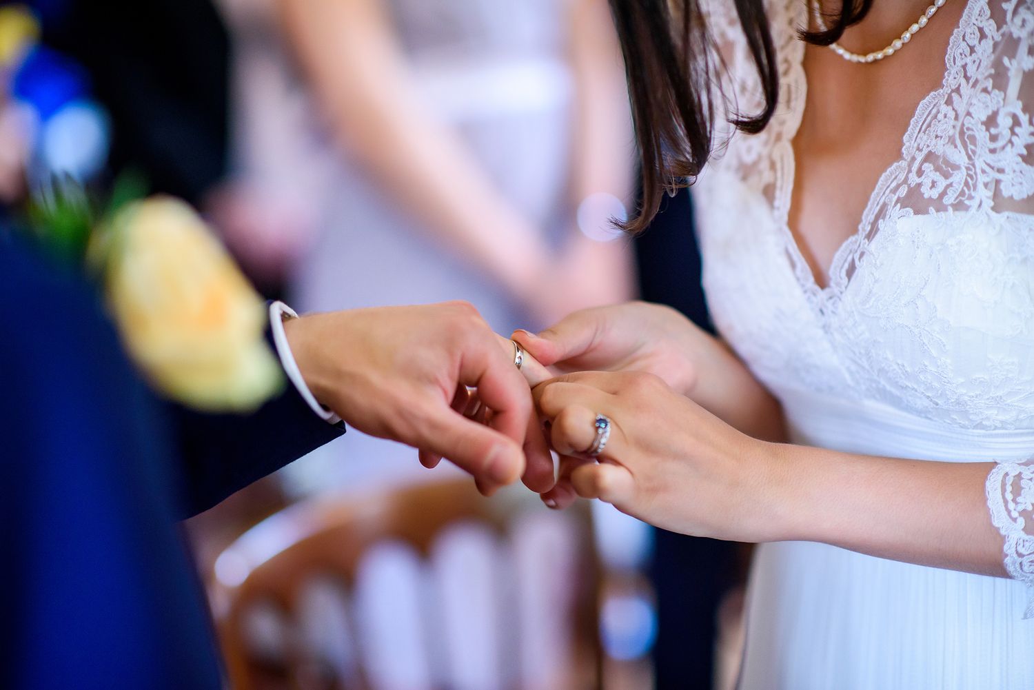 Wedding couple holds hands and exchanges rings during ceremony.