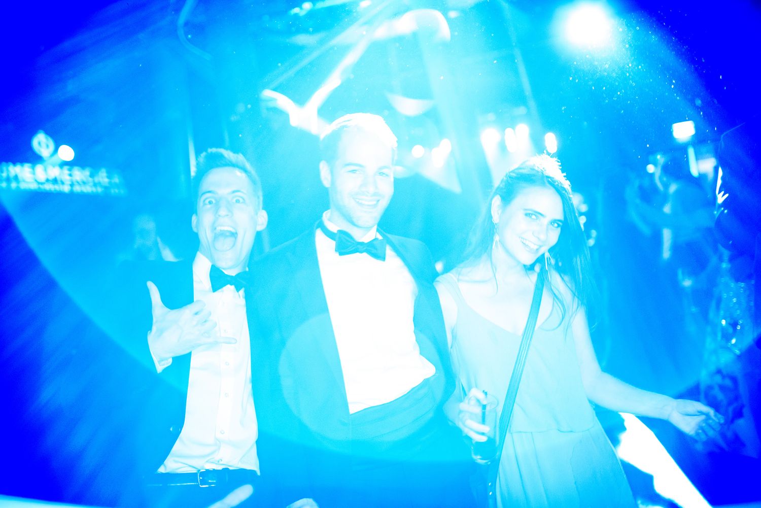 People enjoying a nightclub party under bright blue strobe lights and atmospheric effects.
