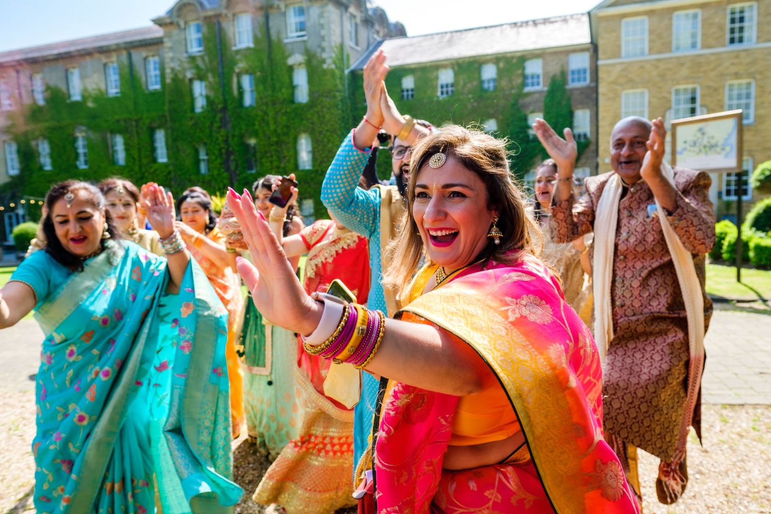 Colorful outdoor celebration with dancers in vibrant saris performing traditional moves.
