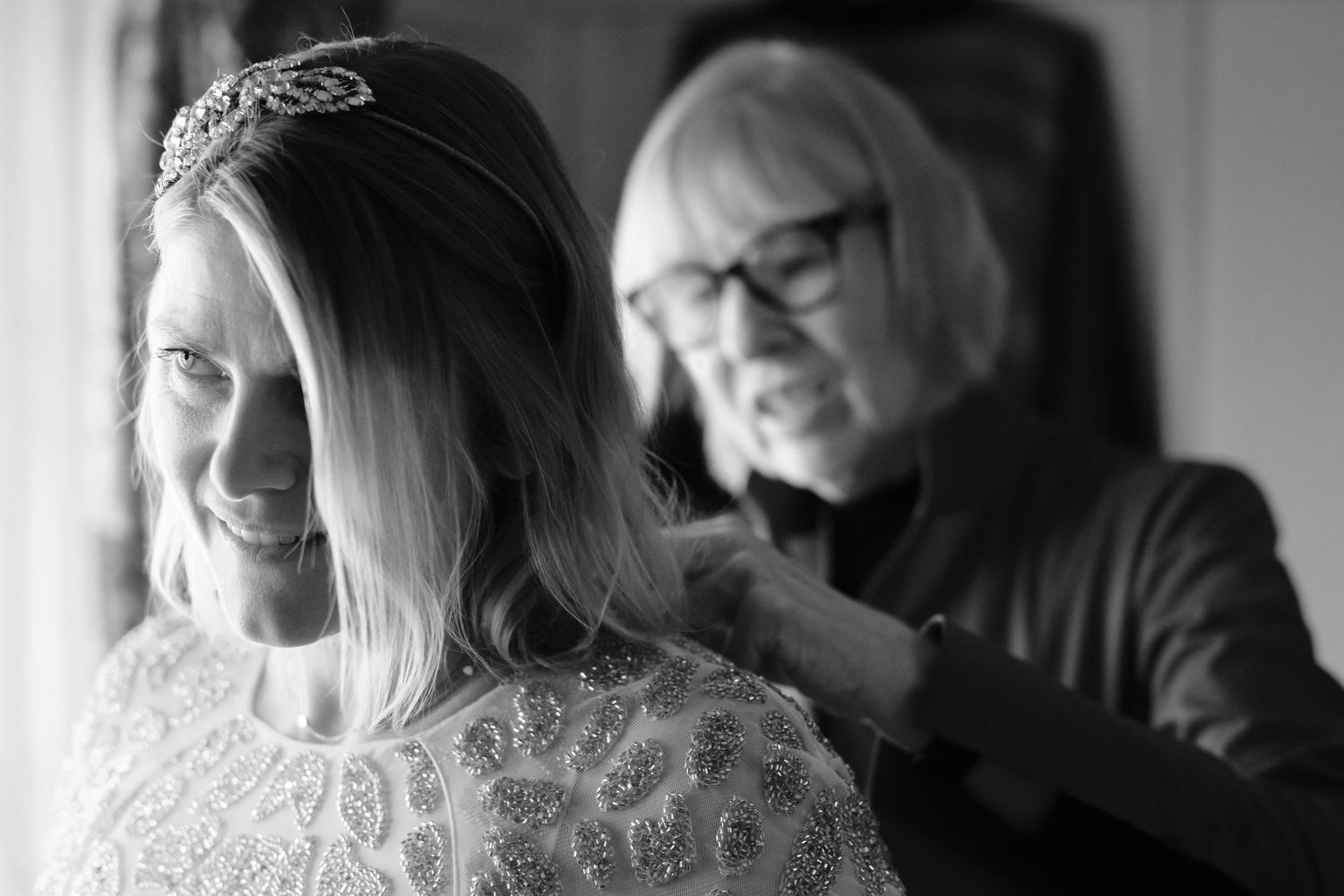 Black and white photo capturing candid laughter and joy during a wedding celebration.
