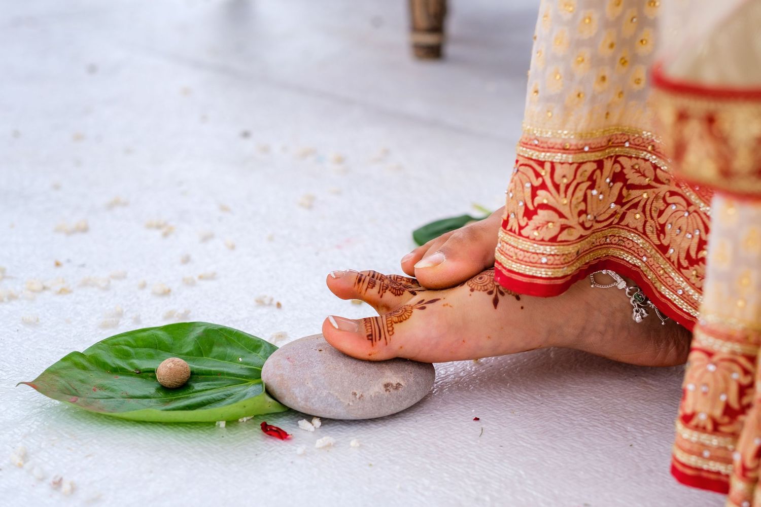 Close-up details of traditional Indian wedding decorations with leaves and stones on white background.