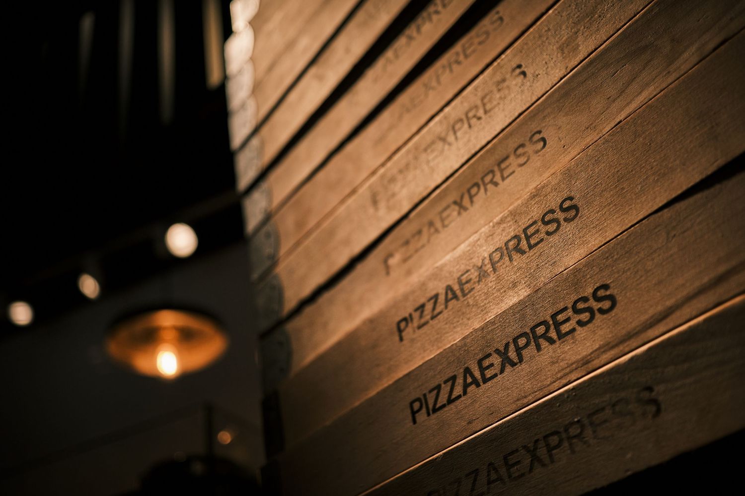 Wood paneled wall with illuminated restaurant signage in moody lighting.