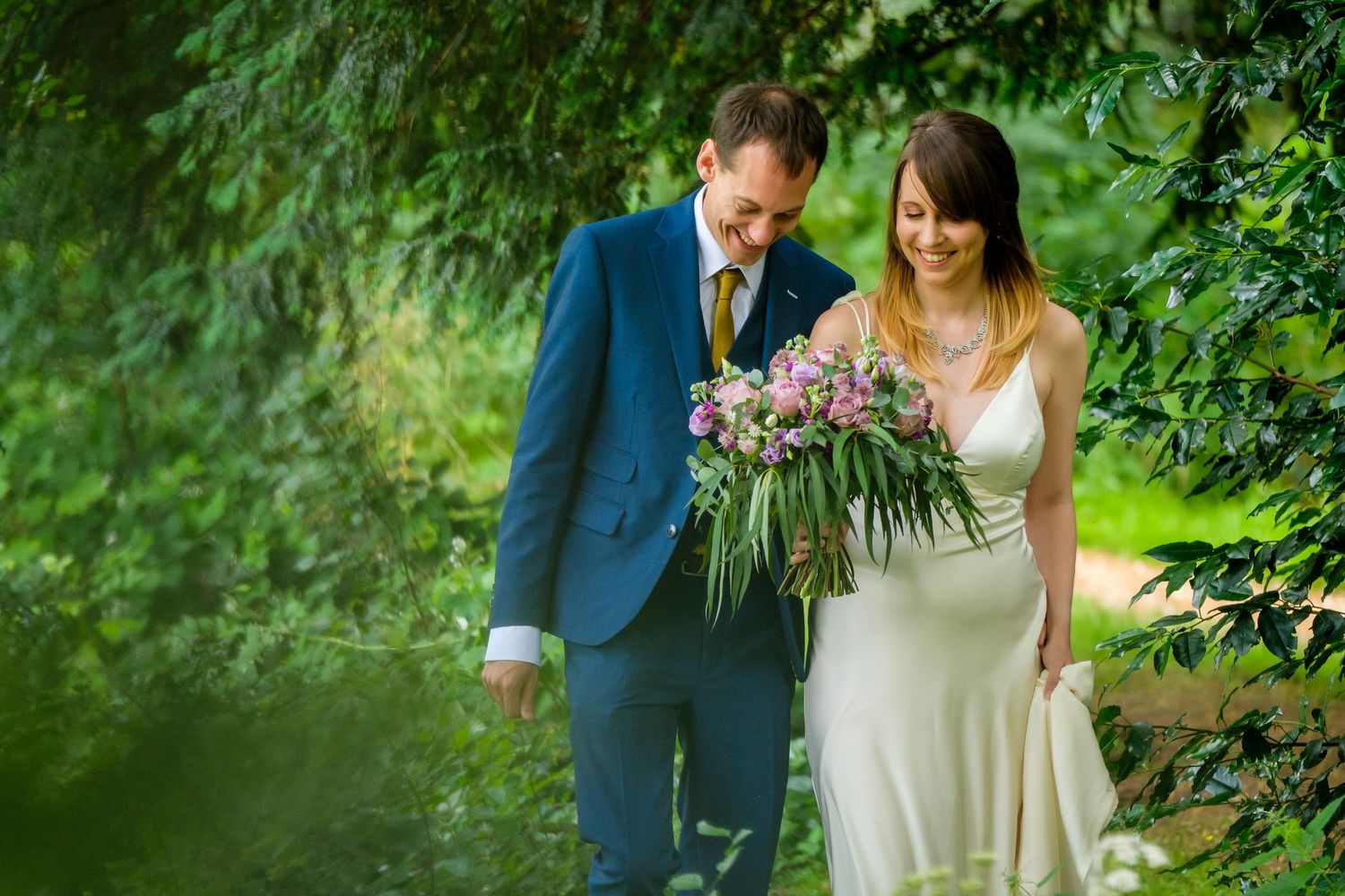 Couple walking through lush garden setting on their wedding day.