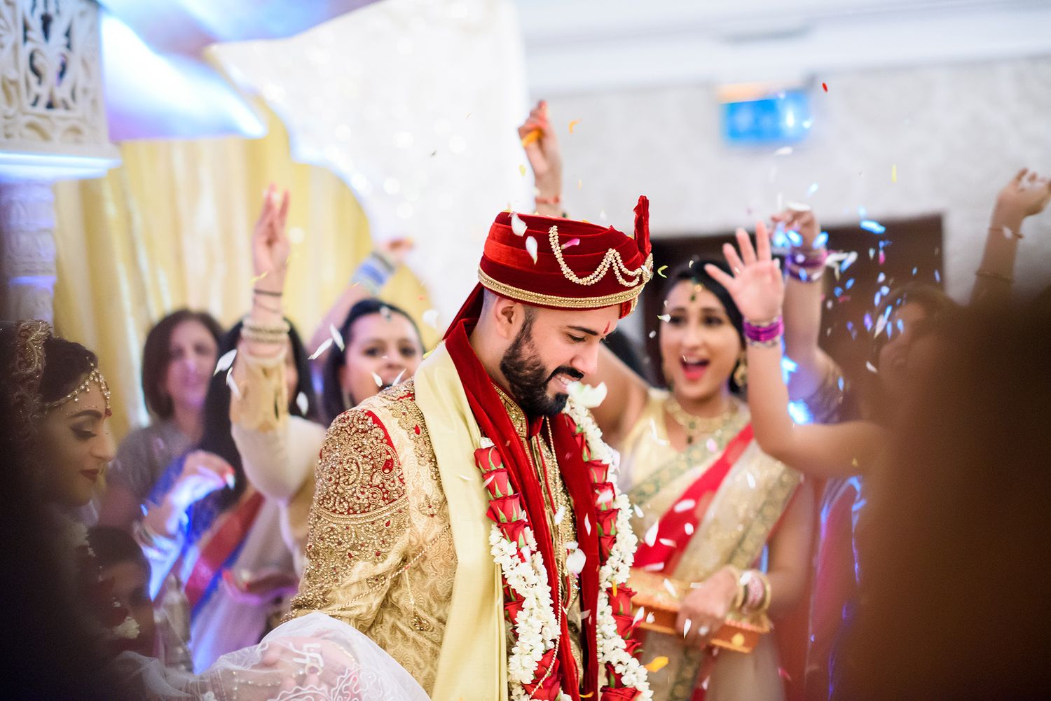 Traditional marriage ceremony taking place under decorated mandap with guests watching.