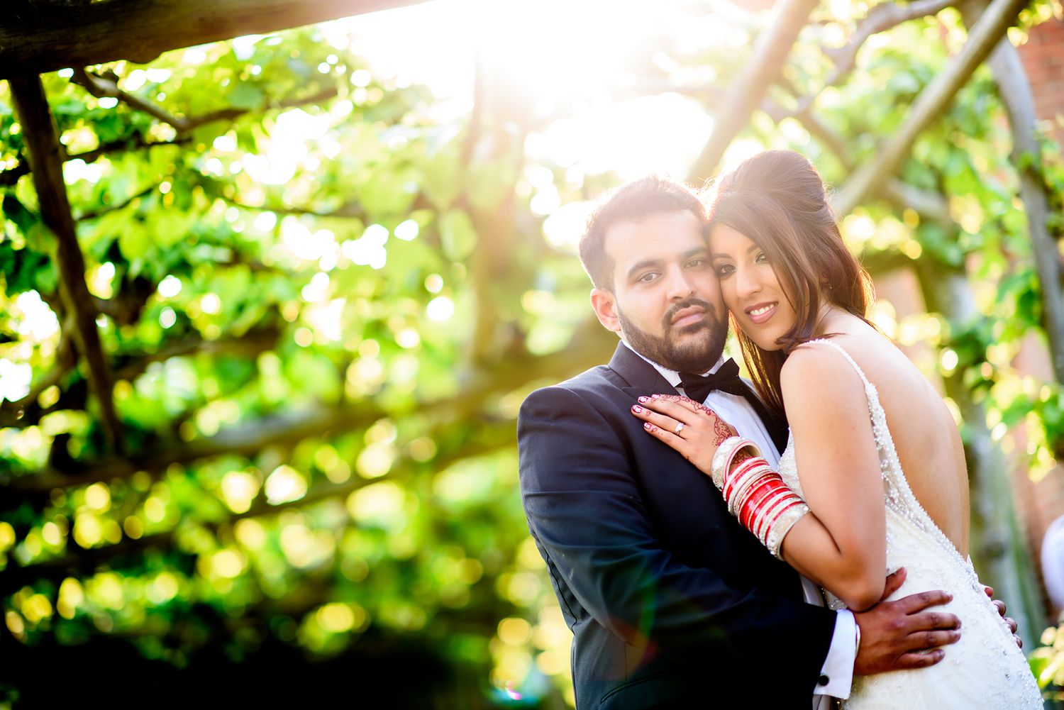 Sunlit wedding portraits captured through natural foliage creating a magical golden hour atmosphere.