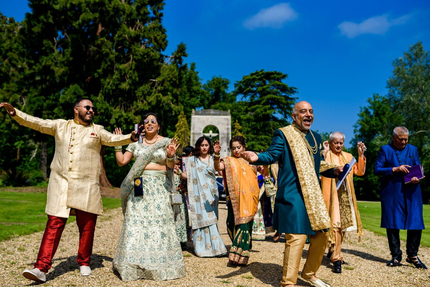 Festive wedding celebration outdoors with group wearing traditional Indian and fusion attire.