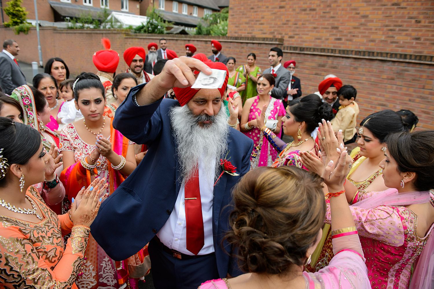 A celebratory moment at a cultural event with guests in traditional attire gathered around a person pouring drinks.