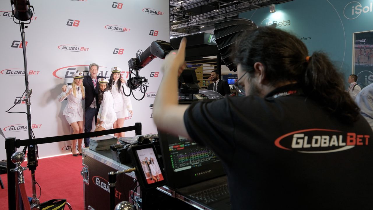 Professional camera setup and lighting equipment at a media event with red carpet.
