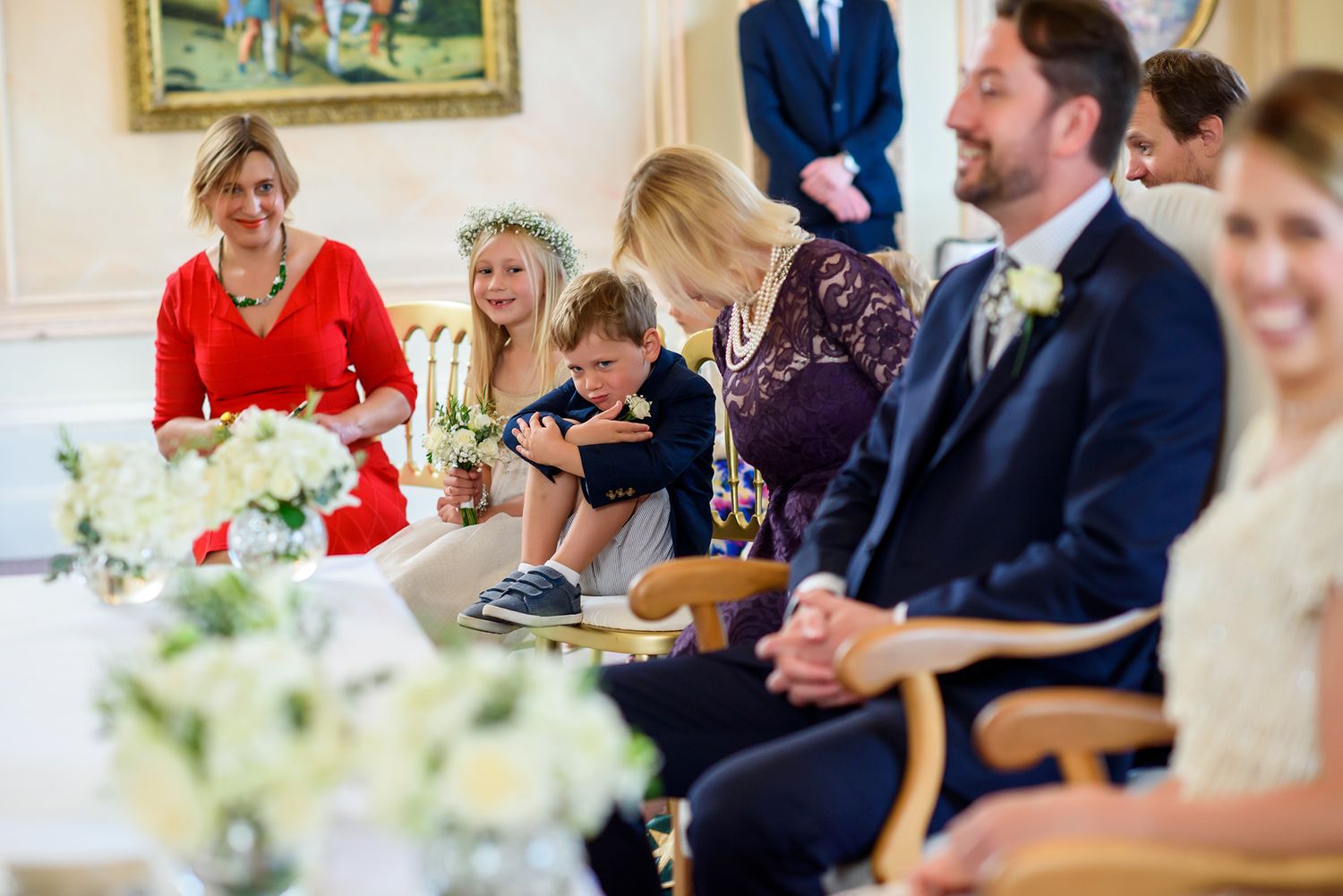Wedding guests seated at tables decorated with white floral centerpieces during reception.