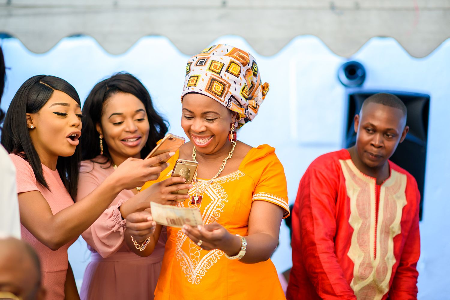 Group of people celebrating and dancing joyfully at an outdoor event under a white tent.