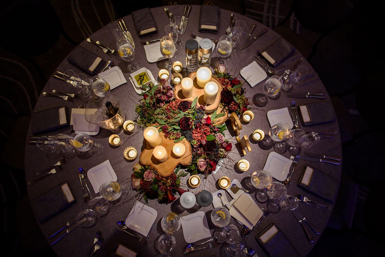 Overhead view of decorated round dining tables with candlelit centerpieces and formal place settings.