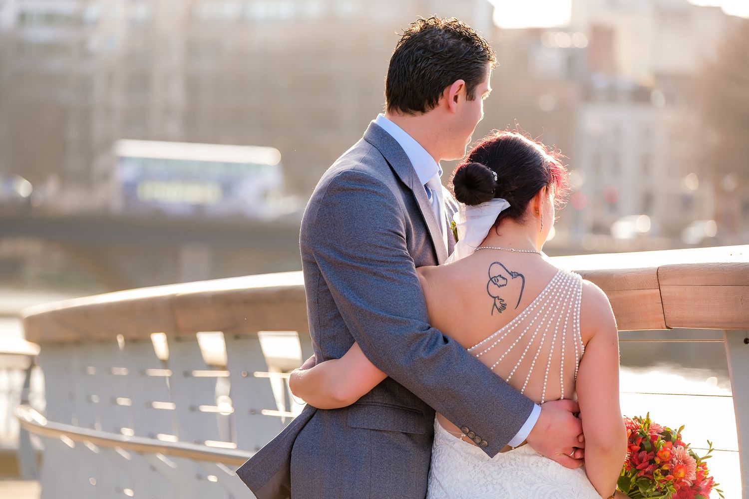 Intimate moment between newlyweds during golden hour on waterfront deck.